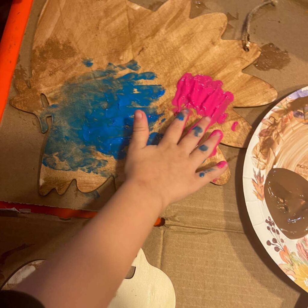 little hands painting a wooden turkey