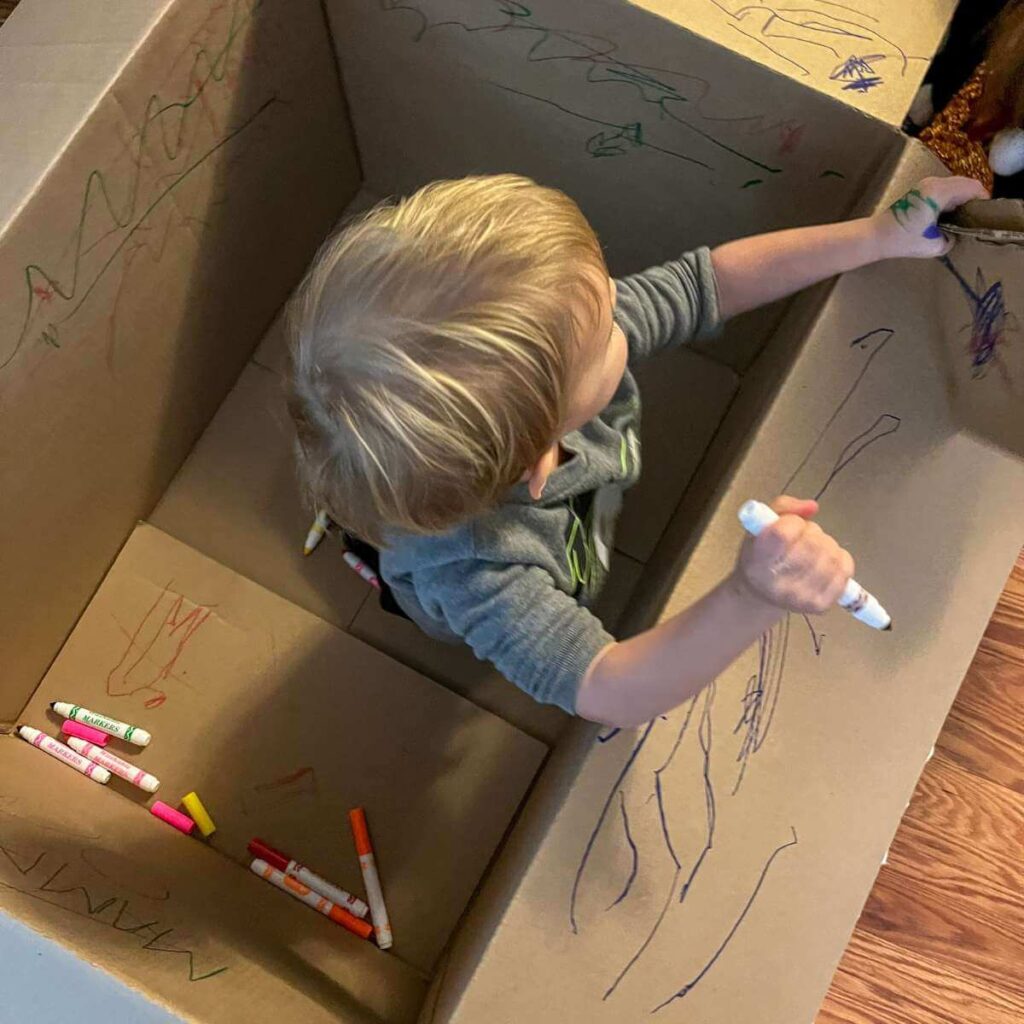 toddler coloring on a cardboard box