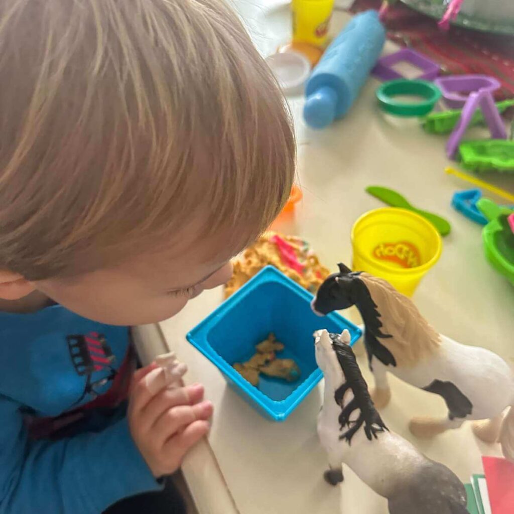 toddler playing with horses and play dough
