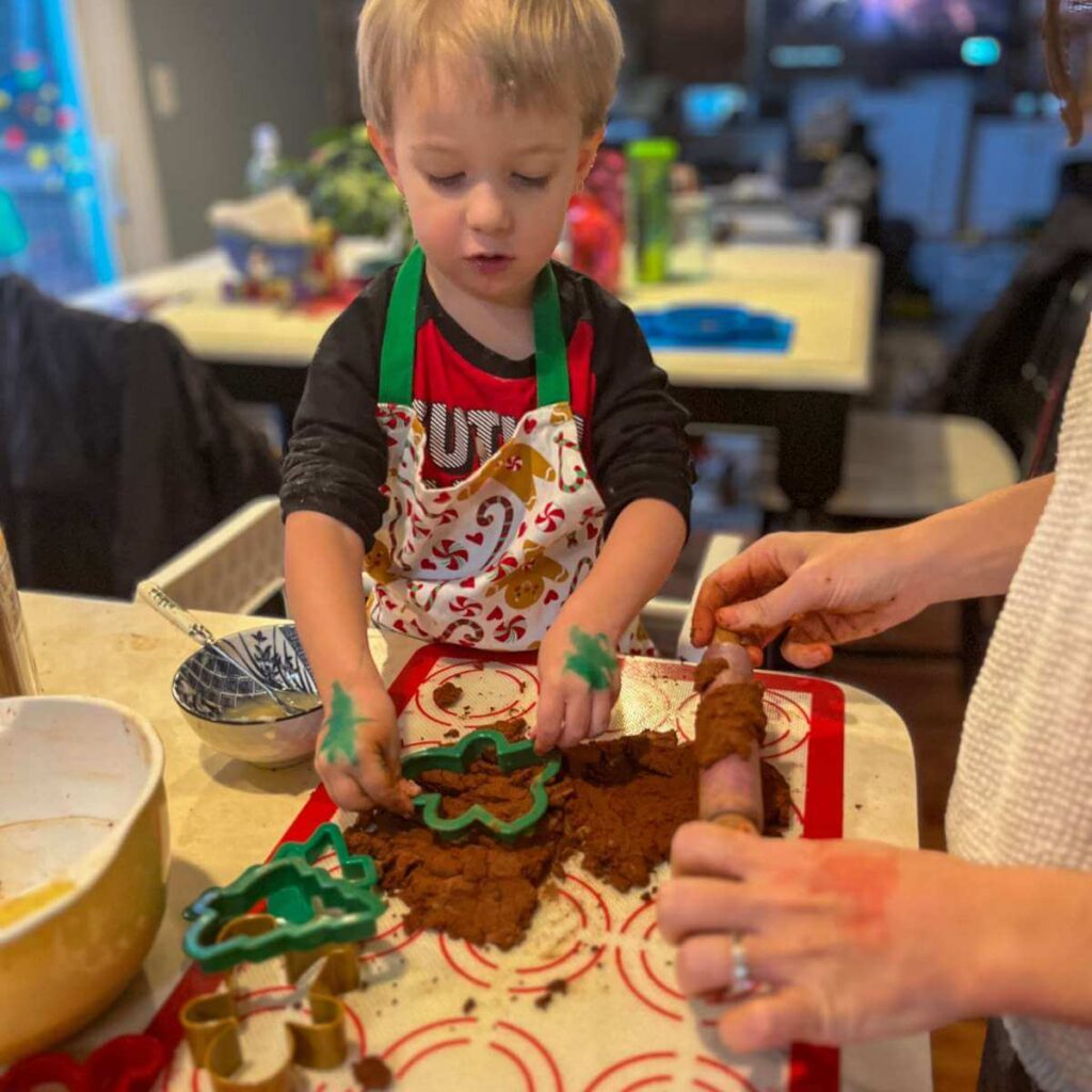 little boy using cookie cutters on dough