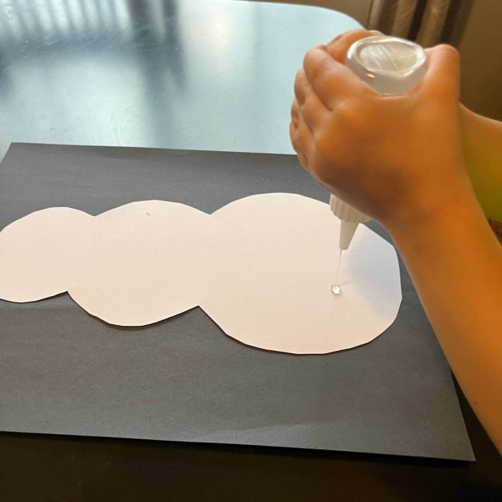 child putting glue on paper