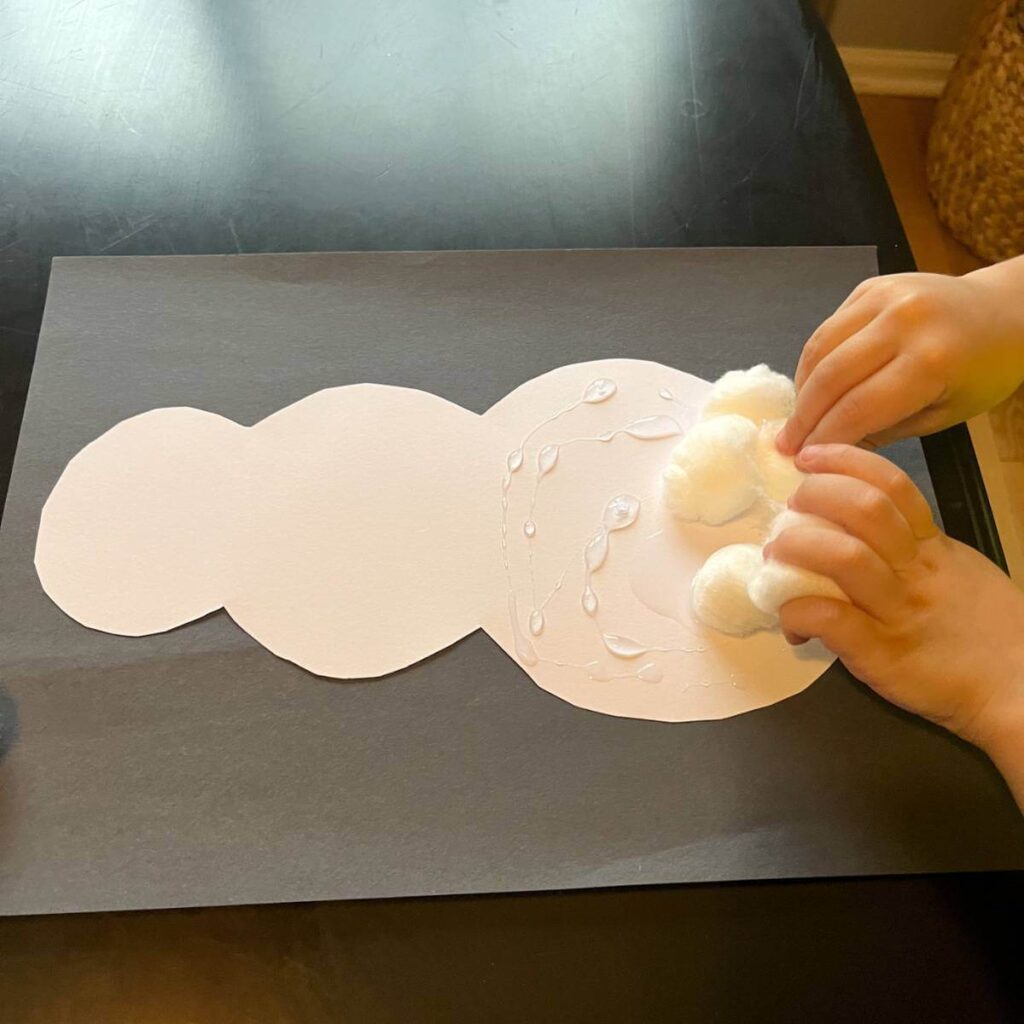 child putting cotton balls on snowman craft